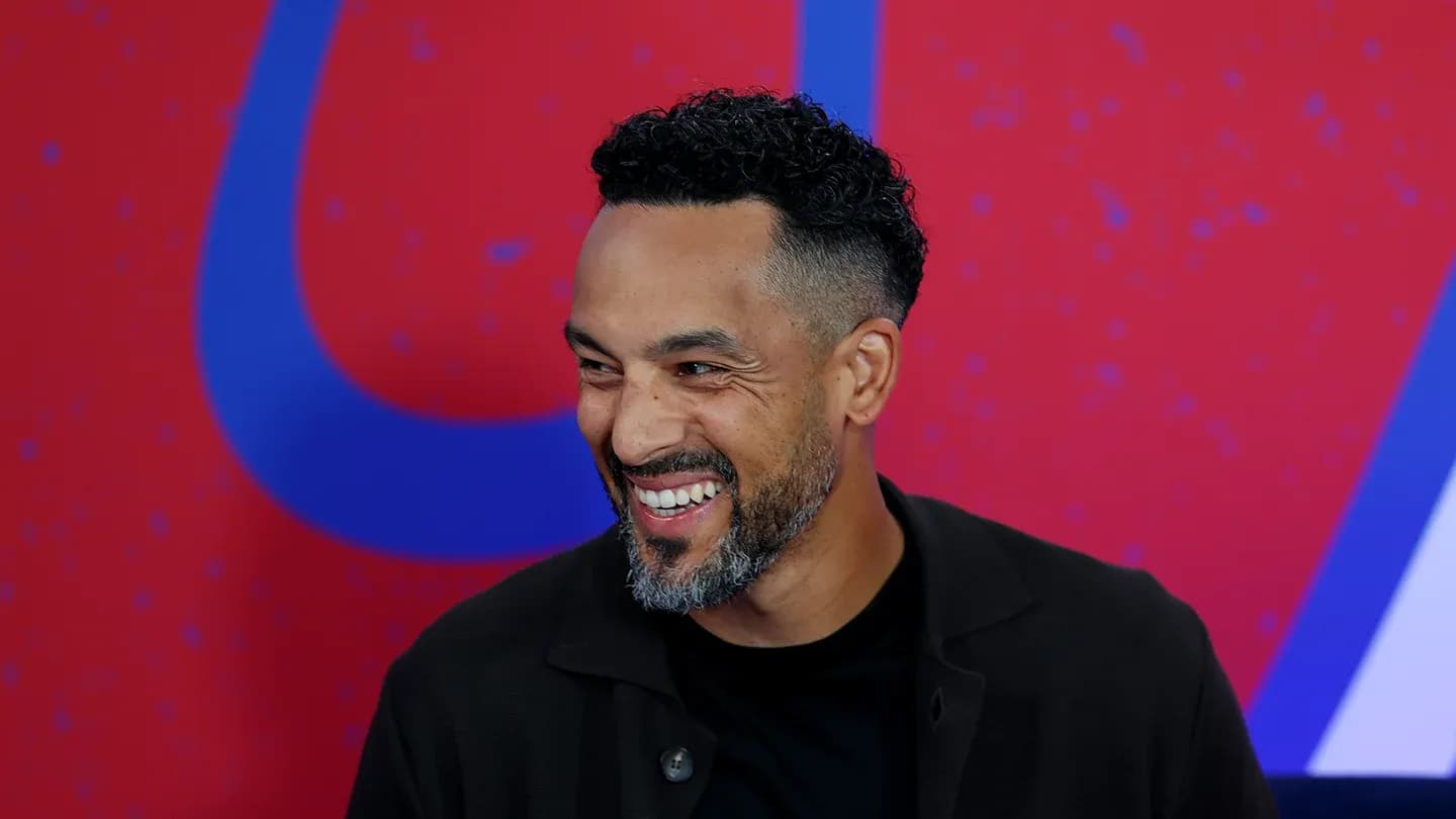 Man smiling during a press event with colorful background Man smiling during a press event with colorful background